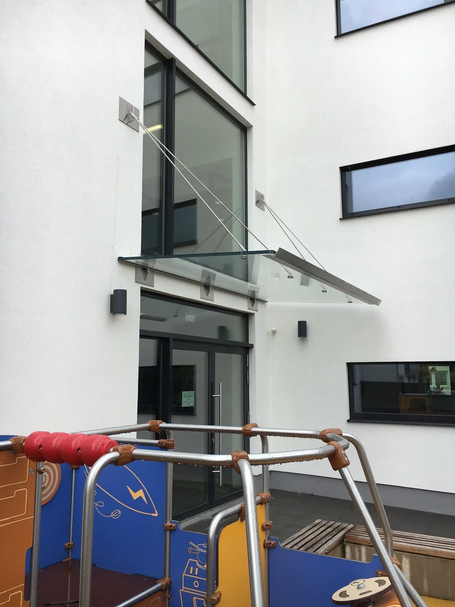 Auvent vitré suspendu par tirants inox au-dessus de l'entrée d'un bâtiment scolaire — auvent vitré Luxembourg — Vitralux Bradtke
