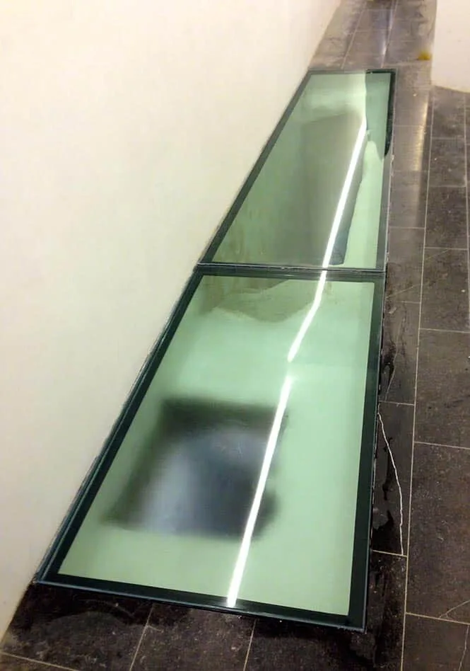 Détail d'une bande de sol en verre praticable insérée dans un dallage en pierre — Vitralux Bradtke