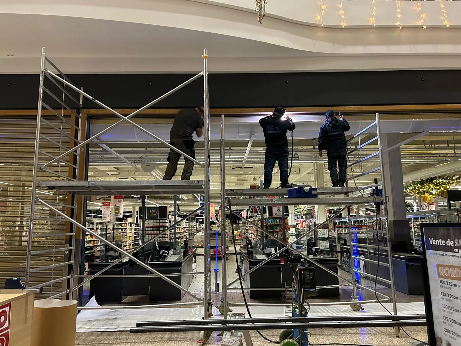 Équipe sur échafaudage installant un écran de cantonnement de fumée de nuit — Auchan Kirchberg — Vitralux Bradtke