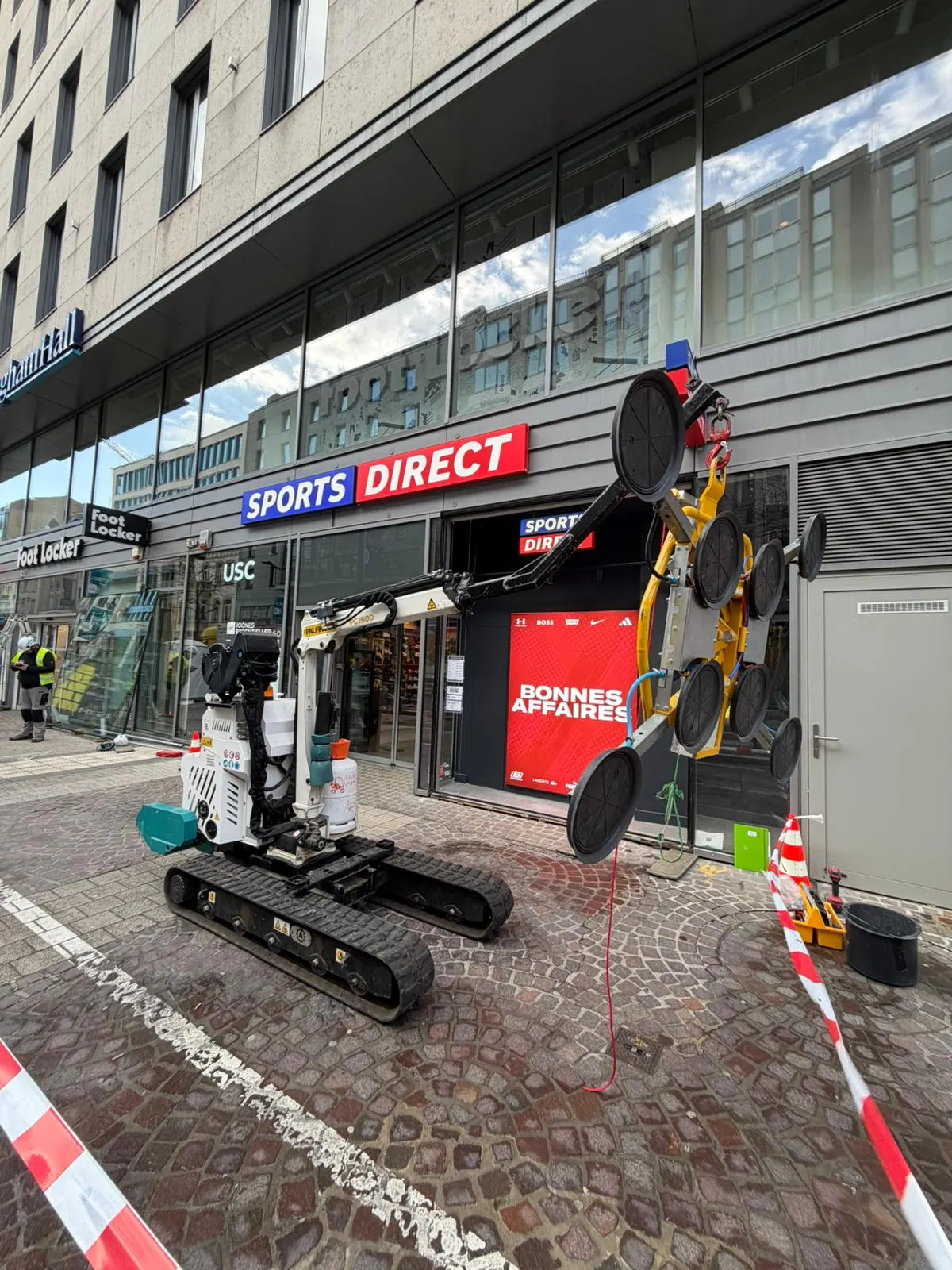 Mini-grue à chenilles avec ventouse installée en rue devant un commerce — Vitralux