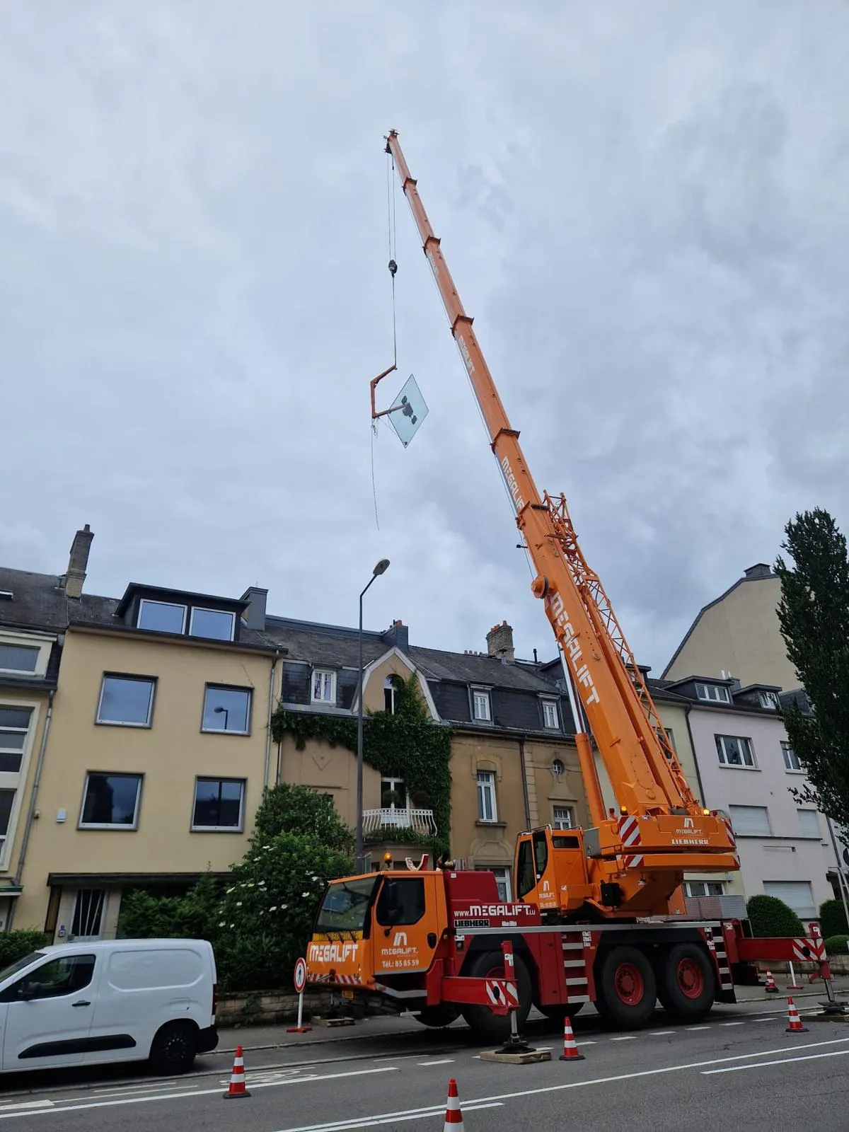 Grue mobile levant un vitrage au-dessus des toits — accès difficile — Vitralux Luxembourg