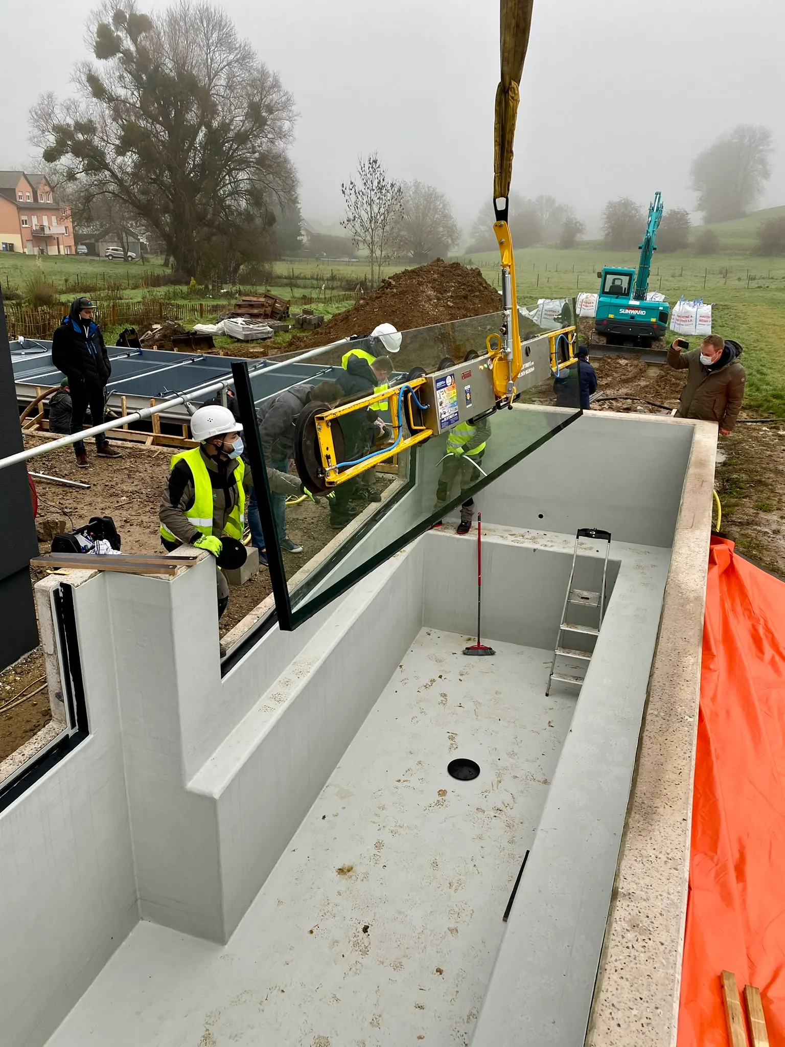 Grande paroi vitrée installée dans le bassin en béton d'une piscine à débordement — vitrage bassin sur mesure Luxembourg — Vitralux Bradtke
