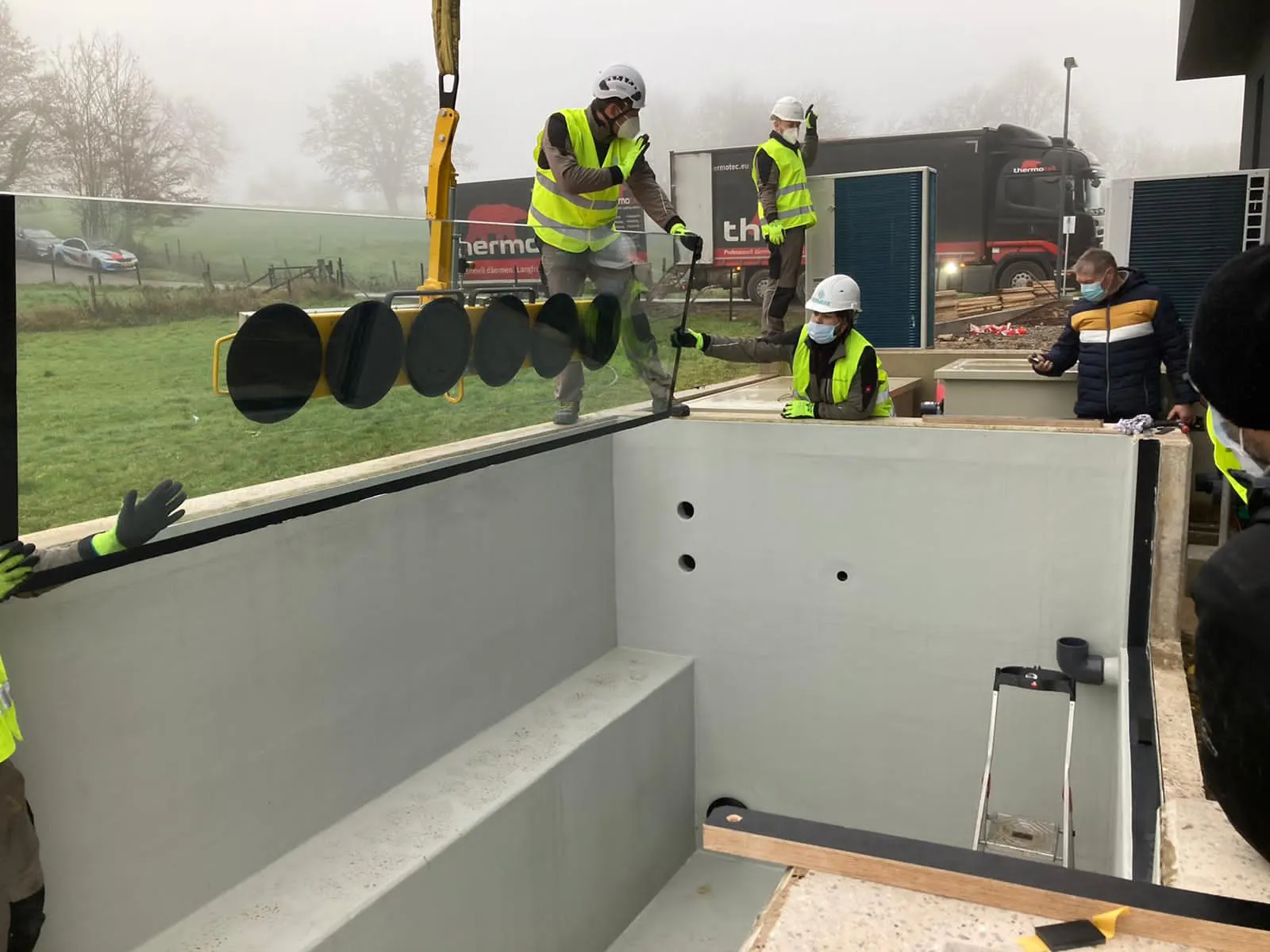 Descente et pose d'une paroi vitrée dans la feuillure béton d'un bassin